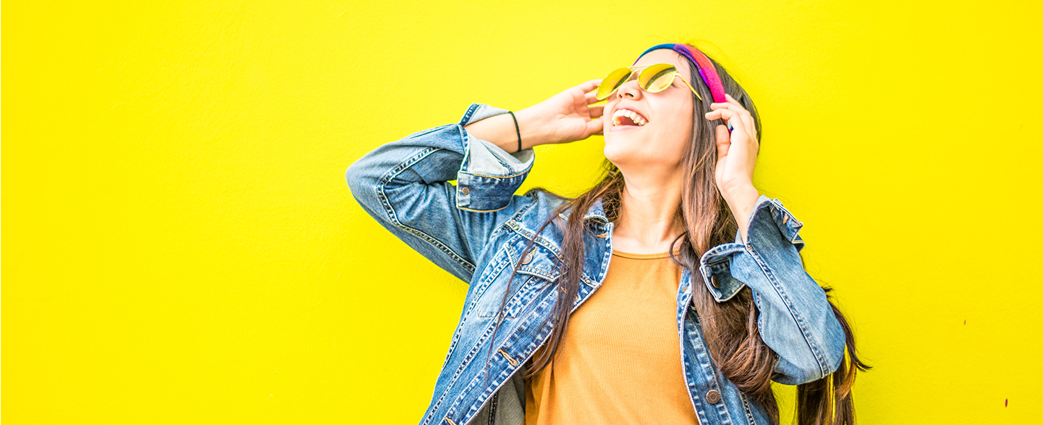 Hero image of a girl smiling while looking up against a yellow background.